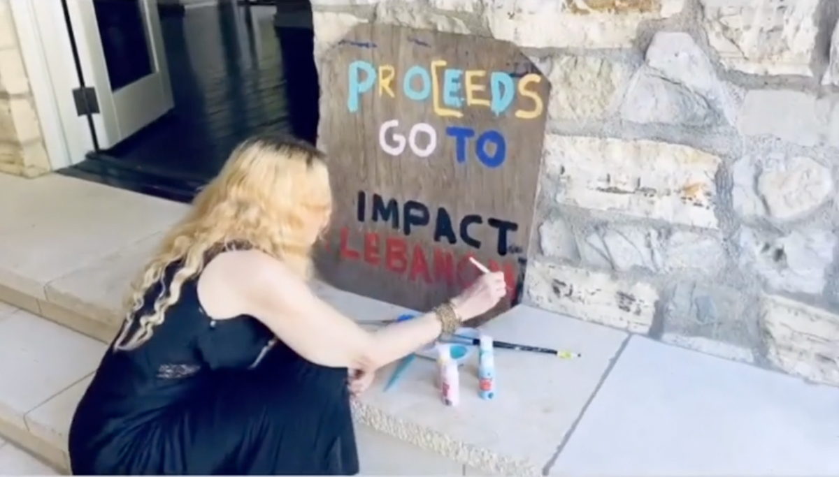 In a video posted to the 61-year-old star’s Instagram account, Madonna can be seen sitting on the ground painting a sign that read 'Proceeds go to Impact Lebanon.''