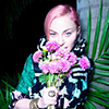 Madonna with pink hair, posing with pink flowers in a green dress.